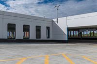 an empty parking lot is shown with several windows and a yellow line across the sidewalk