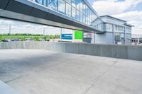 an empty parking lot is seen from the side with green and white signage in front of an office building