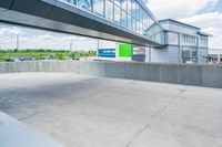 an empty parking lot is seen from the side with green and white signage in front of an office building