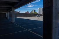 an empty parking lot in a city with tall buildings behind it on a clear day