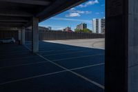 an empty parking lot in a city with tall buildings behind it on a clear day