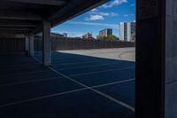 an empty parking lot in a city with tall buildings behind it on a clear day