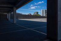 an empty parking lot in a city with tall buildings behind it on a clear day