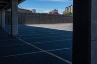 an empty parking lot in a city with tall buildings behind it on a clear day