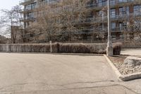 a stop sign in the middle of a street near a fence and tree line building