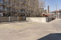 an empty parking lot next to a large brick building with no people in it and one is standing