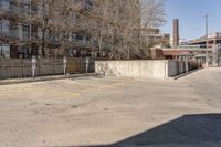 an empty parking lot next to a large brick building with no people in it and one is standing