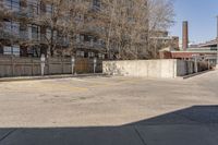 an empty parking lot next to a large brick building with no people in it and one is standing