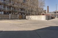 an empty parking lot next to a large brick building with no people in it and one is standing