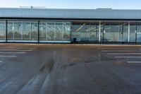 an empty parking lot with large glass walls around the building and a sign that reads'stop