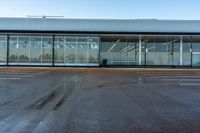 an empty parking lot with large glass walls around the building and a sign that reads'stop