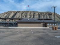 an empty parking lot with some flags on top of it and mountains in the background