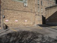 a parking lot with an empty red stop sign in front of a tall brick building