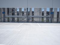 a empty parking lot with white lines and blue signs on it and an entrance way