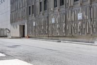 two parking meters on the side of a large building next to a street with parking spaces and several signs