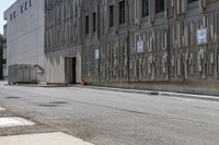 two parking meters on the side of a large building next to a street with parking spaces and several signs