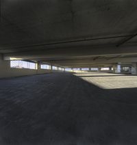 a parking lot with an overpass in the middle and sun shining on the ground