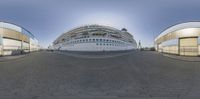 large passenger ship at dock in glass building area of port city, as seen through fisheye lens