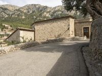 an image of the path to a stone house in the mountainside with trees and rocks around it