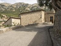 an image of the path to a stone house in the mountainside with trees and rocks around it