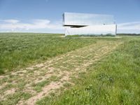 a reflection on the mirror of an empty building in the grass and weeds in the foreground