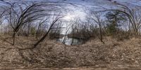 a panoramic view of a path in the woods with water in the distance