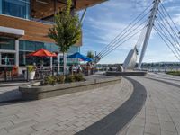 some people sitting and eating on patio furniture near the water in front of a building