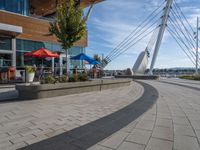 some people sitting and eating on patio furniture near the water in front of a building