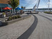 some people sitting and eating on patio furniture near the water in front of a building