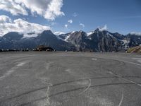 a paved circular field in front of snowy mountains with a view of snow capped mountains