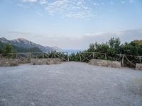 a paved driveway overlooks the water in a mountainous area with green trees on both sides