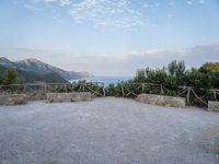 a paved driveway overlooks the water in a mountainous area with green trees on both sides