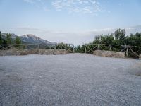 a paved driveway overlooks the water in a mountainous area with green trees on both sides