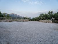 a paved driveway overlooks the water in a mountainous area with green trees on both sides