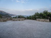 a paved driveway overlooks the water in a mountainous area with green trees on both sides