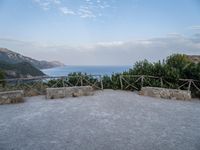 a paved driveway overlooks the water in a mountainous area with green trees on both sides