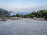 a paved driveway overlooks the water in a mountainous area with green trees on both sides