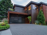 the driveway is paved with pavers between a brick and tree with plants surrounding it