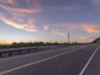 a truck driving down a paved highway at dusk near a rural area in the region