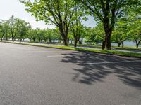 a paved parking lot is surrounded by lush trees on a sunny day along a river