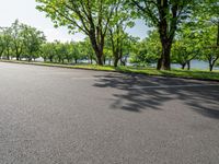 a paved parking lot is surrounded by lush trees on a sunny day along a river