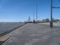 the path by the water has been paved with bricks and flags on it and flags along it