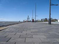 the path by the water has been paved with bricks and flags on it and flags along it