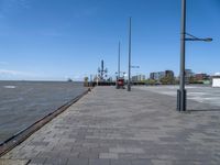 the path by the water has been paved with bricks and flags on it and flags along it