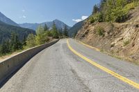 a bike is parked on a paved road with mountains in the background and green trees at one end