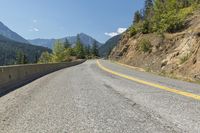 a bike is parked on a paved road with mountains in the background and green trees at one end