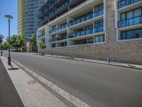 a paved road in front of a building with many windows and a traffic light in front of it