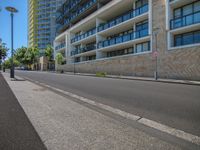 a paved road in front of a building with many windows and a traffic light in front of it