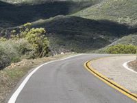 a lone motorcycle on a paved road in the mountains by a mountain range with trees