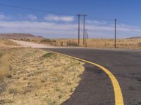 the paved road is painted yellow and black in the desert area, surrounded by power lines